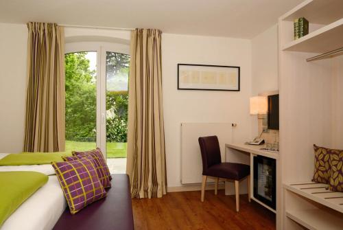 um quarto de hotel com uma cama, uma secretária e uma janela em Das Landhaus Hauptmann em Pörtschach am Wörthersee