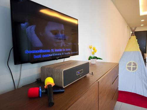 a flat screen tv sitting on top of a wooden entertainment center at The Shore Residences by Amanjiwa in Melaka