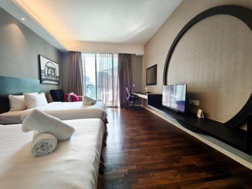 a hotel room with two beds and a flat screen tv at The Shore Residences by Amanjiwa in Melaka