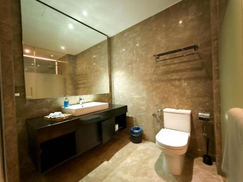 a bathroom with a toilet and a sink and a mirror at The Shore Residences by Amanjiwa in Melaka