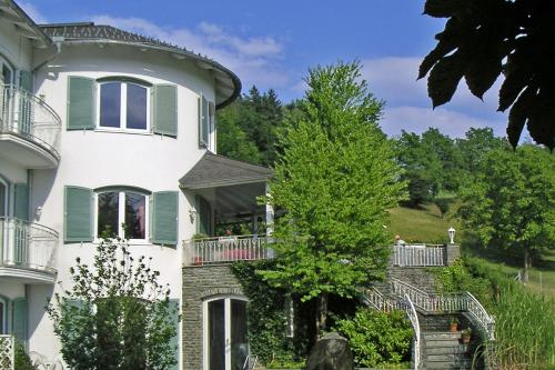 Une grande maison blanche avec des volets verts et des escaliers dans l'établissement Das Landhaus Hauptmann, à Pörtschach am Wörthersee