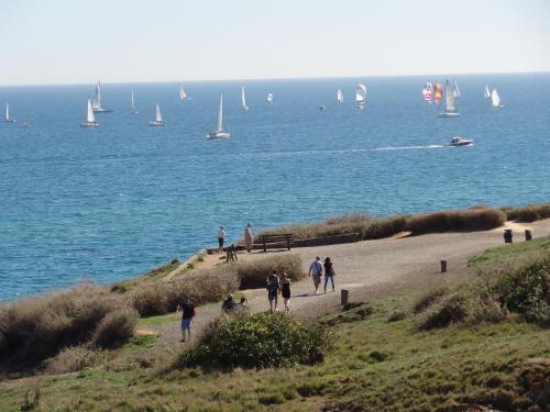 a group of people walking down a beach with sailboats at Hôtel Bellevue Cap d'Agde in Cap d'Agde