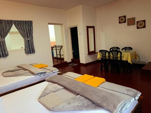 two beds in a room with a table and chairs at Daffodil Resort Haputale in Haputale