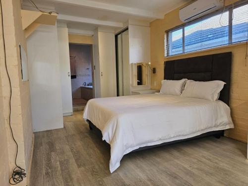 De GrendelにあるCozy Calm Apartment with Poolの窓のある大きな白いベッドのある寝室