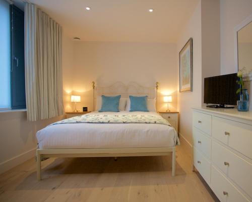 a bedroom with a bed with blue pillows and a television at Citystay - Pringle House in Cambridge