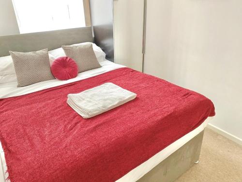 a bed with a red blanket and pillows on it at Nested 4-Bedrooms retreat in Walsall -Elegant 3 Bathrooms-Sleeps 9 in Walsall