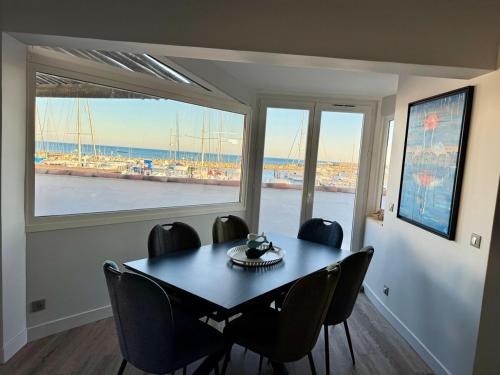 une salle à manger avec une table et des chaises et une fenêtre dans l'établissement Vue Mer Climatisé - 11 pers, à Saintes-Maries-de-la-Mer