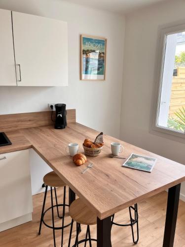 une table en bois dans une cuisine avec deux tasses et du pain dans l'établissement Maison Kerheol, à Bénodet