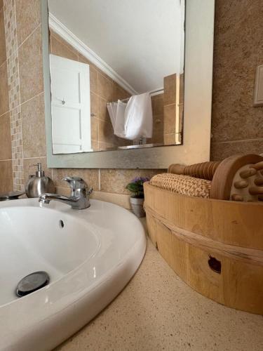 a bathroom with a sink and a mirror and a tub at Alojamento Praia do Norte in Leiria