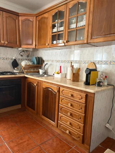 a kitchen with wooden cabinets and a counter top at Alojamento Praia do Norte in Leiria