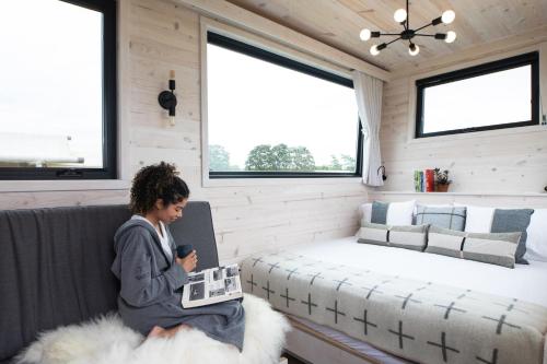 a woman sitting on a couch in a tiny house at Collective Retreats Governors Island in New York
