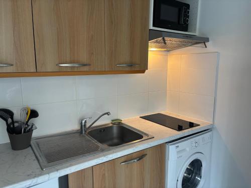 une cuisine avec un évier et une machine à laver dans l'établissement Studio Calif, face tram proche Mer, à Nice