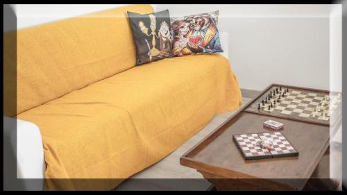 a yellow couch with a chessboard on a table at La casa di Belle in Castelchiodato