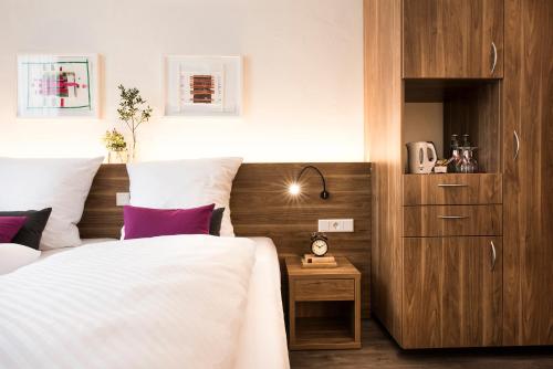 Schlafzimmer mit einem Bett mit weißer Bettwäsche und lila Kissen in der Unterkunft Alexianer Hotel am Wasserturm in Münster