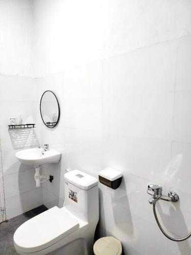a white bathroom with a toilet and a sink at Muối Homestay in Ấp Khánh Phước (1)