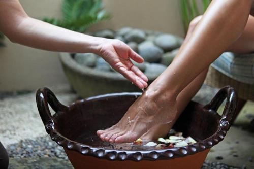 a woman is washing her feet in a bowl at InterContinental Costa Rica at Multiplaza Mall by IHG in San José
