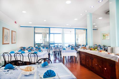 a dining room with tables and chairs with blue napkins at Hotel Bellaria in Bellaria-Igea Marina