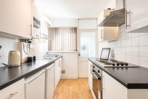 a kitchen with white cabinets and a black counter top at Peaceful Room in Doncaster Shared House w Kitchen in Doncaster