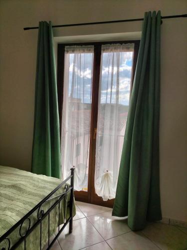 a bedroom with a window with green curtains at Arra Camere Sirolo - Rooms & Suite in Sirolo