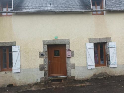 a house with two windows and a wooden door at Happy Homes in Plouyé