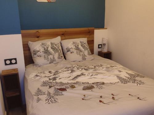 - un lit doté d'un couvre-lit blanc avec des oiseaux dans l'établissement Studio cabine 4 pers 2* avec équipements pratiques à Valloire - FR-1-263-588, à Valloire