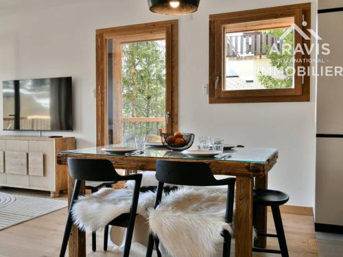 une cuisine avec une table en bois, des chaises et une fenêtre dans l'établissement Apt cocoon pour familles, vue montagne, parking, wifi - FR-1-391-207, au Grand-Bornand
