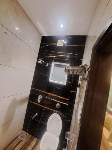a bathroom with a toilet with a black tiled floor at Hotel Blossom Inn in Amritsar