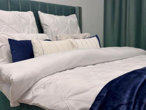 a bed with white sheets and blue pillows at Smile - BrandNew Apart with FreeUndergroundParking, large Balcony, near Shopping Centers in Bistriţa