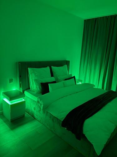 a green bedroom with a bed with a green light at Smile - BrandNew Apart with FreeUndergroundParking, large Balcony, near Shopping Centers in Bistriţa