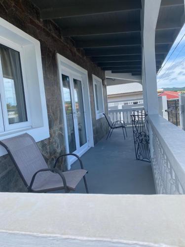 a porch with two chairs and a table on a house at Renicas Cottage in Micoud