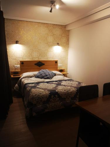 a bedroom with a bed and a table and lights at hospederia rincon de leon in León