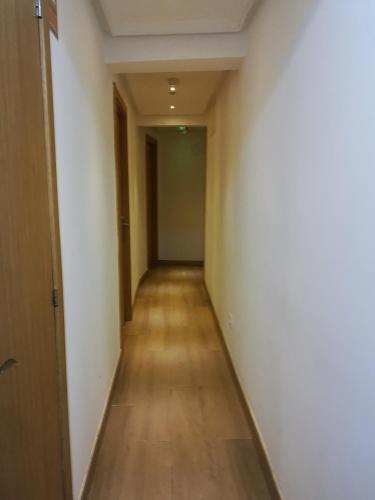 an empty hallway with a long wooden floor and white walls at hospederia rincon de leon in León
