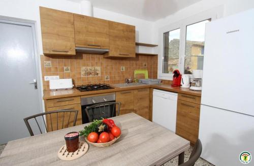 une cuisine avec une table avec un bol de fruits dessus dans l'établissement Gîte de la Ferme des Rosières, à La Garde-Adhémar