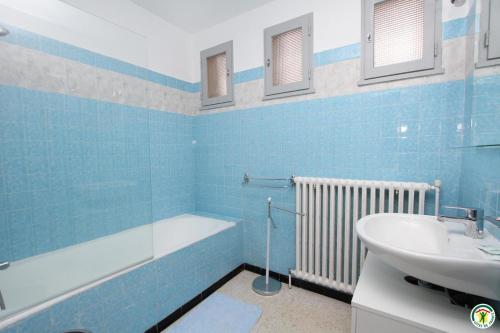 La salle de bains bleue est pourvue d'un lavabo et d'une baignoire. dans l'établissement Gîte de la Ferme des Rosières, à La Garde-Adhémar