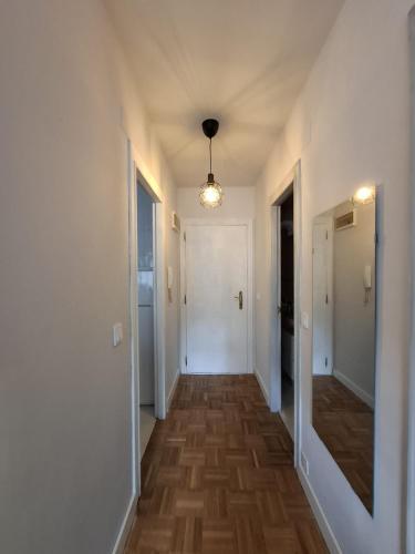 a hallway with white walls and wooden floors and a light fixture at Apartamento Dobra in Cangas de Onís