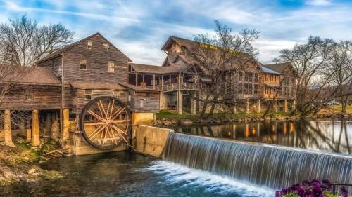 an old mill and waterwheel in front of a house at Our Mountain Memories by Avada Properties in Pigeon Forge