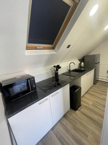 une cuisine avec un comptoir noir avec un micro-ondes dans l'établissement coccon 7, à Nogent-sur-Oise