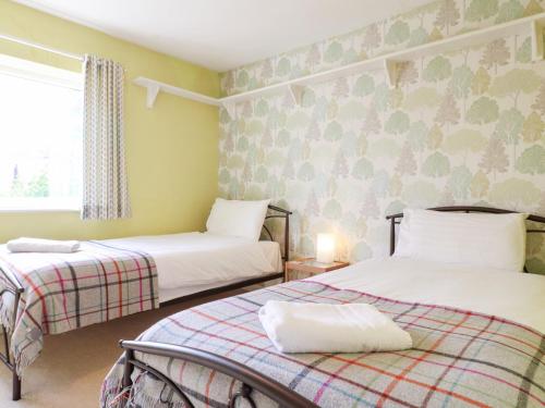 a bedroom with two beds and a window at Jasmine Cottage in Bakewell