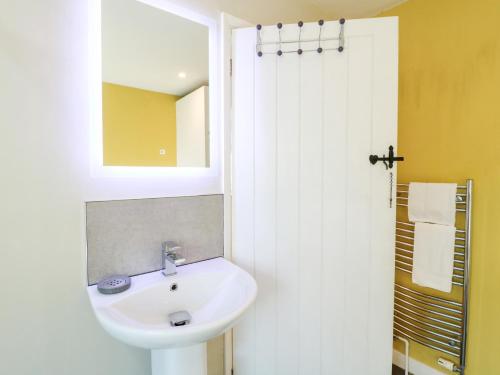 a white bathroom with a sink and a mirror at Jasmine Cottage in Bakewell