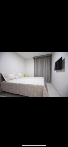a bedroom with a white bed and a tv at Bastos e Silva in Caldas Novas
