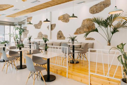 a restaurant with tables and chairs and plants at Arcade Hotel Athens in Athens