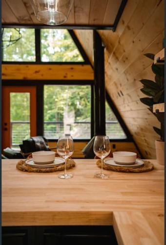 a wooden table with two wine glasses on it at My Tennessee A-Frame by Avada Properties in Sevierville