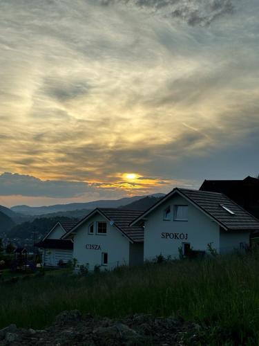 two white houses with the sunset in the background at Cisza i Spokój in Szczawnica