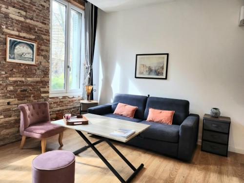 un salon avec un canapé bleu et une table dans l'établissement Luxine One - Appartement 4 pers - Entre Canal et Gare Matabiau, à Toulouse