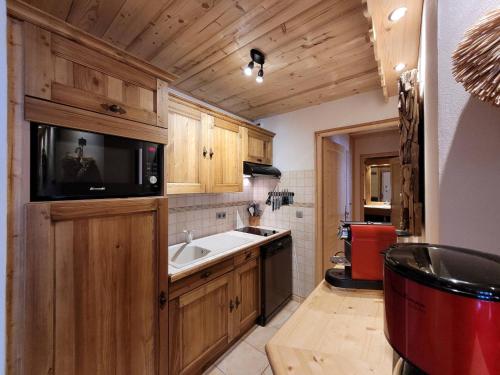 Il comprend une cuisine avec un évier et une télévision murale. dans l'établissement Confort alpin : T3 proche pistes, parking, Wifi - FR-1-598-74, aux Gets