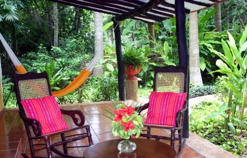 two chairs and a table with a vase of flowers at Hacienda Chichen Resort and Yaxkin Spa in Chichén-Itzá