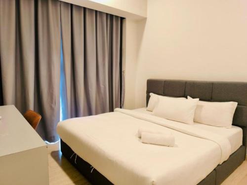 a bedroom with a large white bed with a window at Star Residence KLCC By Cozy in Kuala Lumpur