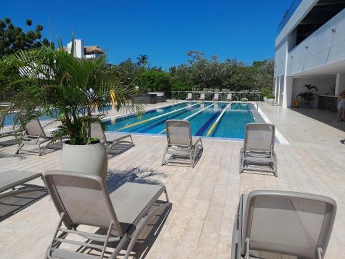 a swimming pool with lounge chairs and a palm tree at ESPECTACULAR APARTAMENTO EN SAMARIA CLUB DE PLAYA smr in Gaira