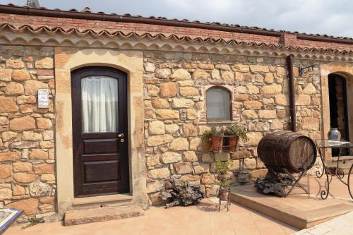 a stone house with a black door and a barrel at Le Querce di Cota in Troina