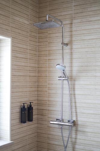 a shower in a bathroom with a wooden wall at Silver Globe in Albufeira